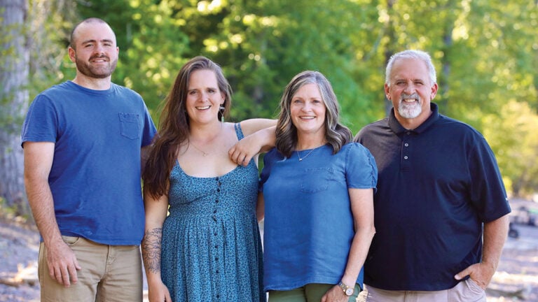 A Judd family photo, with two men and two women, wearing different shades of blue, in front of some trees.